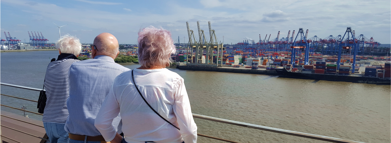Drei ältere Menschen schauen auf Containerhafen in Hamburg